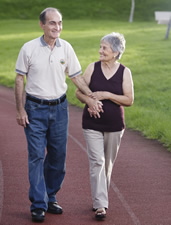caregiver helps elderly man walk outdoors