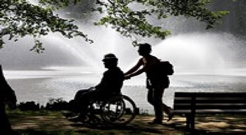 woman pushing man in wheelchair